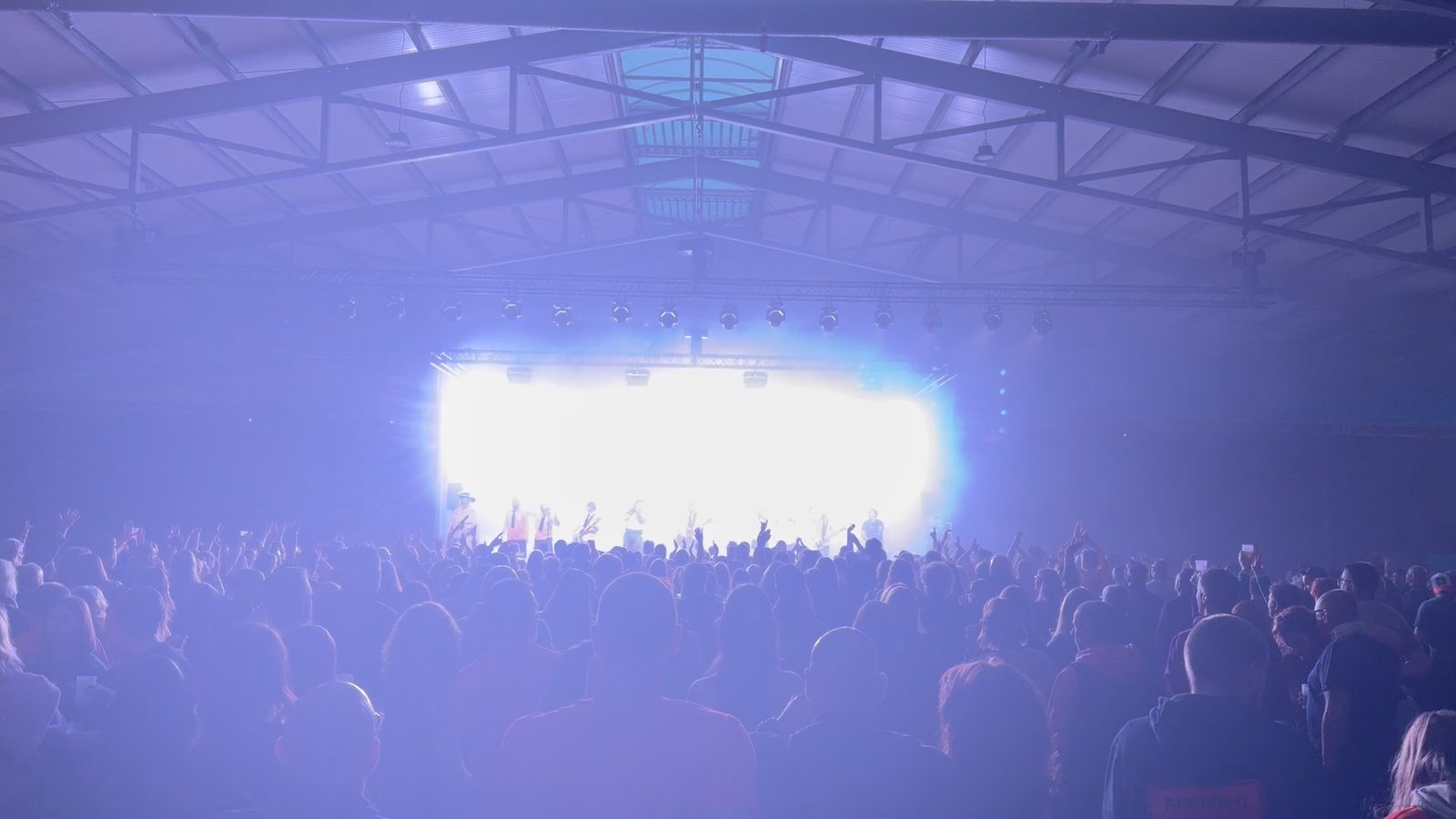 Concert dans un hall, public nombreux, scène éclairée en bleu et blanc